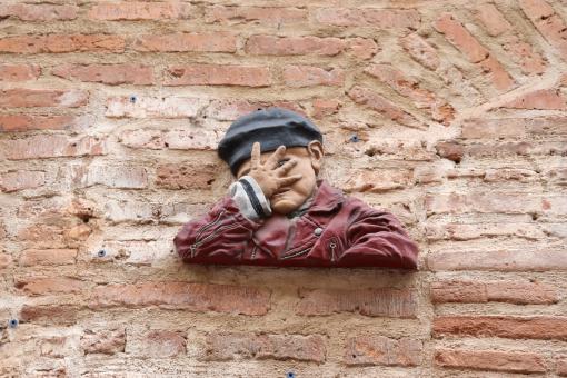 Free Stock Photo of Sculpture on a brick wall of a child hiding his face