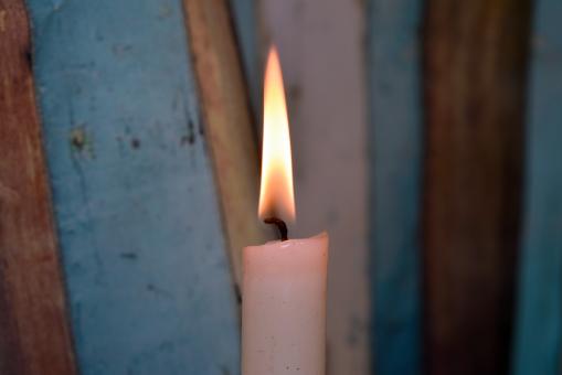 Free Stock Photo of Candle and multi-coloured background behind it