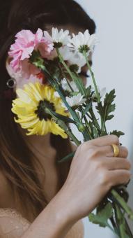 Free Stock Photo of A Woman Hiding Her Face From Colorful Flowers
