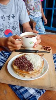 A photo of someone eating a mini martabak and drinking a cup of 