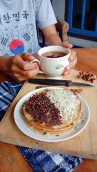 A photo of someone eating a mini martabak and drinking a cup of 