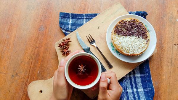 A photo of someone eating a mini martabak and drinking a cup of 