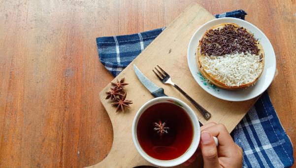 A photo of someone eating a mini martabak and drinking a cup of 
